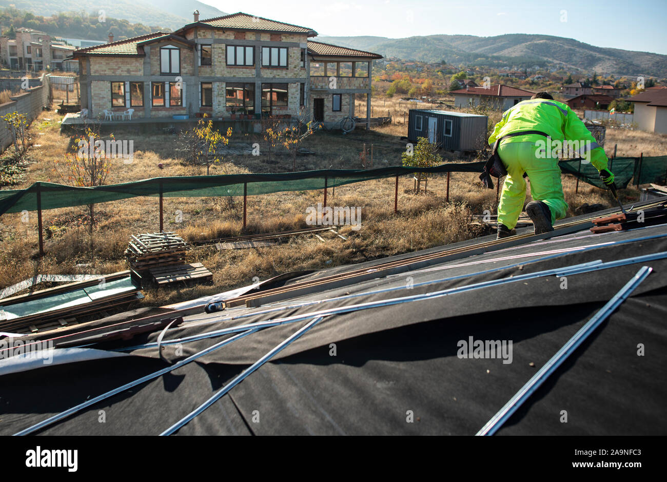 Lavoratore sulla parte superiore della casa rendendo il tetto. La costruzione di una nuova casa con il tetto nero. La riparazione e costruzione di costruzione del tetto. Concezione per coperture, nuovo h Foto Stock