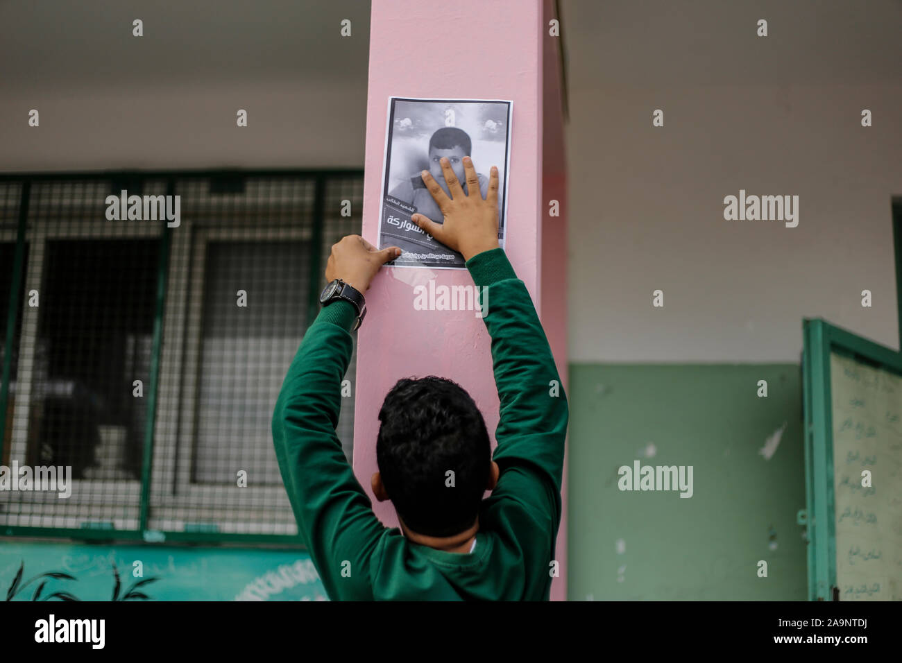 La striscia di Gaza, la Palestina. Xvi Nov, 2019. Un collega si blocca un'immagine su una parete della loro scuola dell'Sawara membro della famiglia che è stato ucciso in un attacco aereo israeliano a Deir al-Balah.Israele disse a colpire la famiglia Sawara e ucciso sette persone per errore. Gruppi per i diritti umani hanno criticato IDF precedenti indagini su possibili crimini di guerra nella Striscia di Gaza. Credito: SOPA Immagini limitata/Alamy Live News Foto Stock