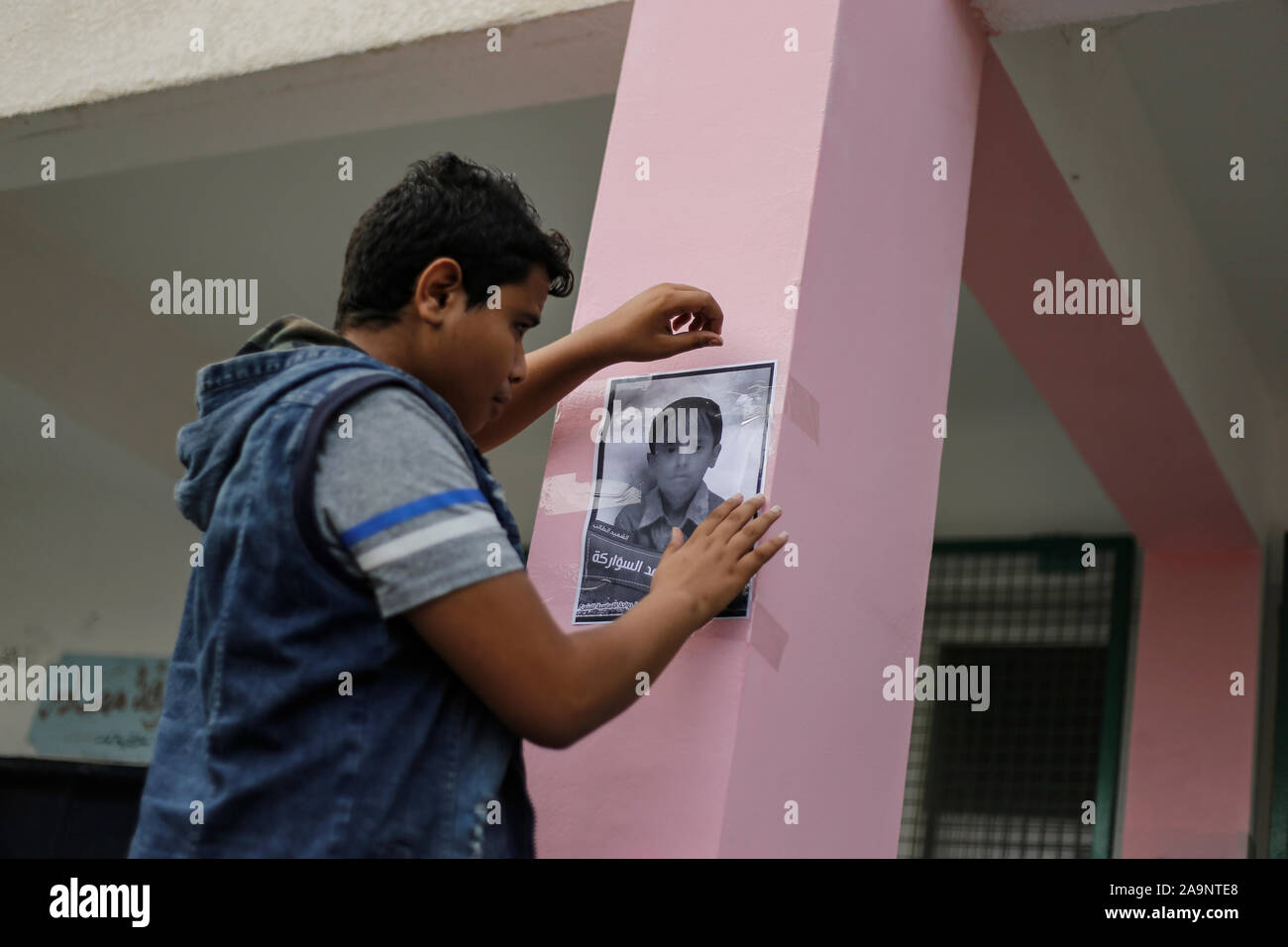 La striscia di Gaza, la Palestina. Xvi Nov, 2019. Un collega si blocca un'immagine su una parete della loro scuola dell'Sawara membro della famiglia che è stato ucciso in un attacco aereo israeliano a Deir al-Balah.Israele disse a colpire la famiglia Sawara e ucciso sette persone per errore. Gruppi per i diritti umani hanno criticato IDF precedenti indagini su possibili crimini di guerra nella Striscia di Gaza. Credito: SOPA Immagini limitata/Alamy Live News Foto Stock