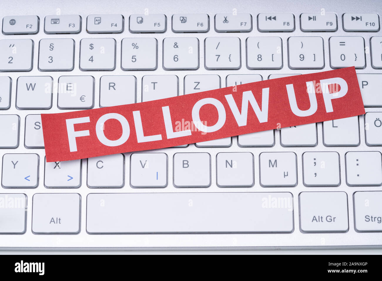 Angolo di Alta Vista della nota carta con Follow Up testo bianco su tastiera in ufficio Foto Stock