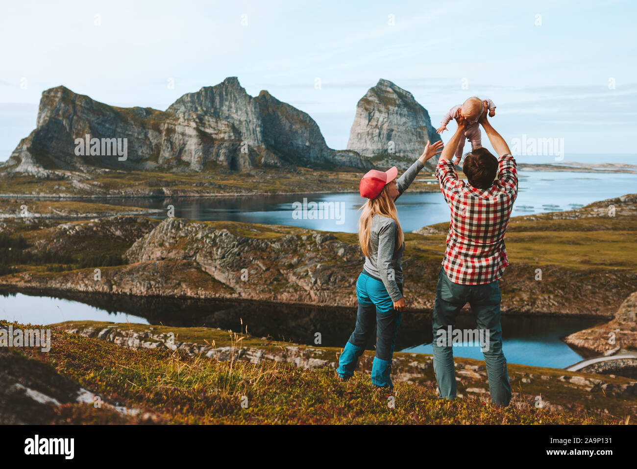 Madre di famiglia e padre tenendo in mano neonato bambino viaggi in Norvegia vacanze outdoor l uomo e la donna di viaggio con kid adventure lifestyle estate Helgeland è Foto Stock