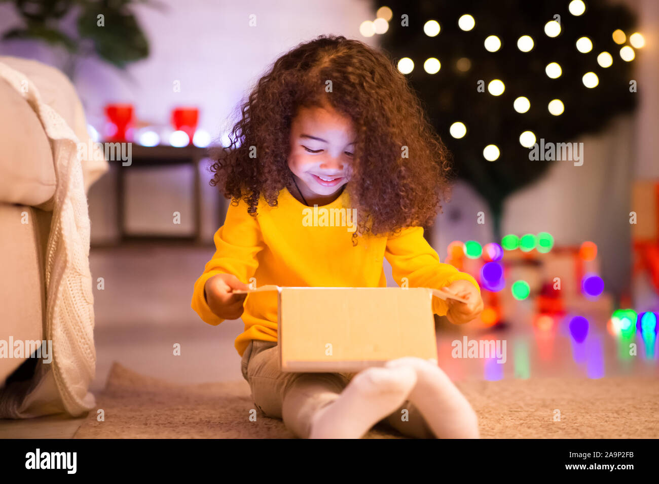 Allegro poco ragazza africana apertura regalo di Natale scatola da Santa Foto Stock