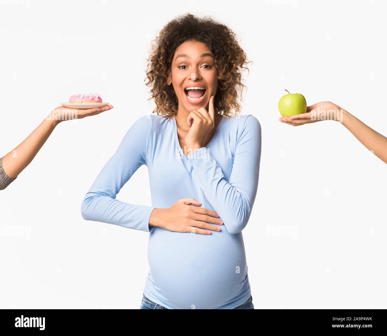 Gravidanza La nutrizione. Emotional donna incinta scegliendo tra apple e ciambella Foto Stock