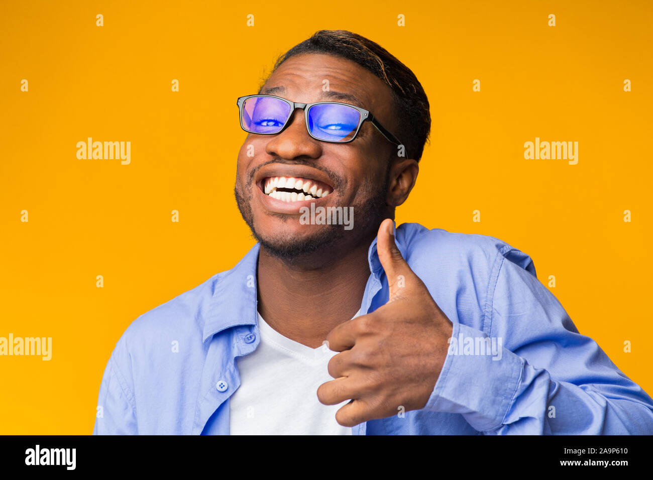 Funny uomo nero gesticolando pollice in alto standing, Studio Shot Foto Stock