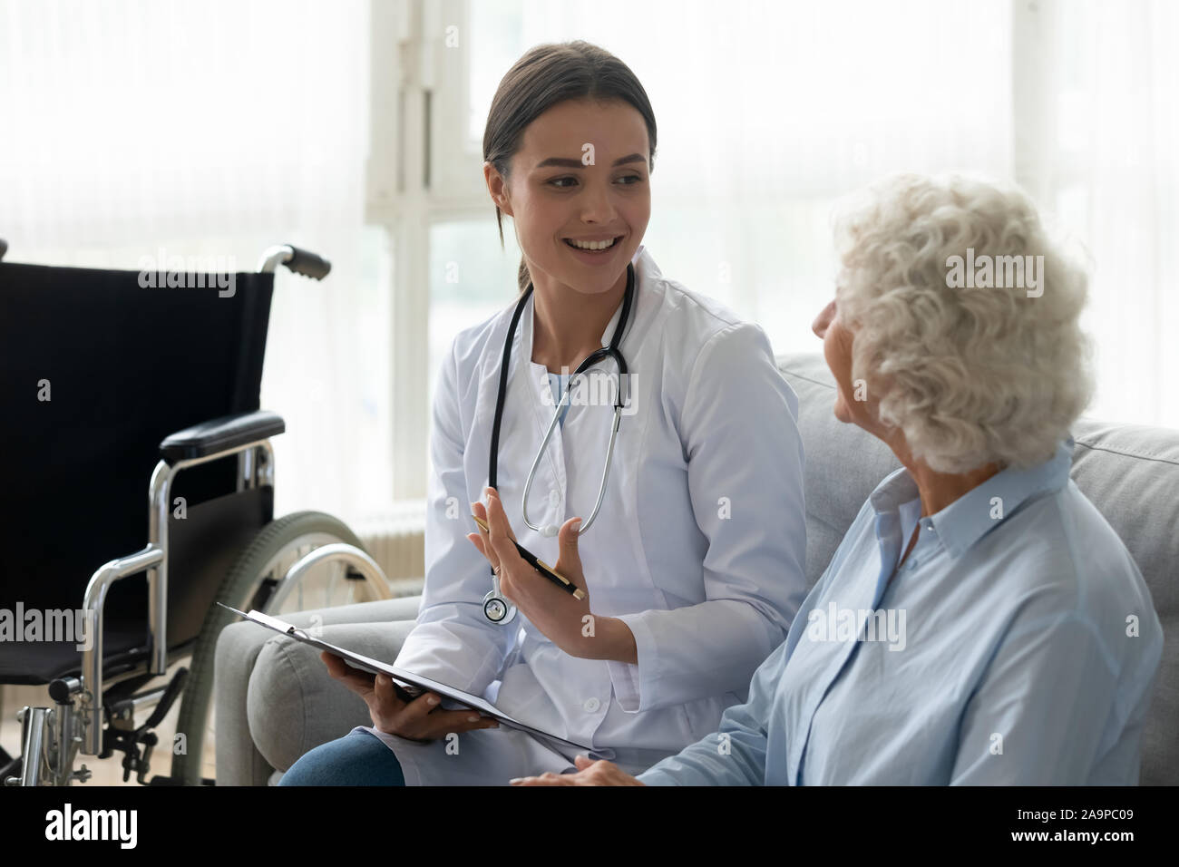 Felice giovane donna medico consultare disabile vecchia nonna paziente Foto Stock
