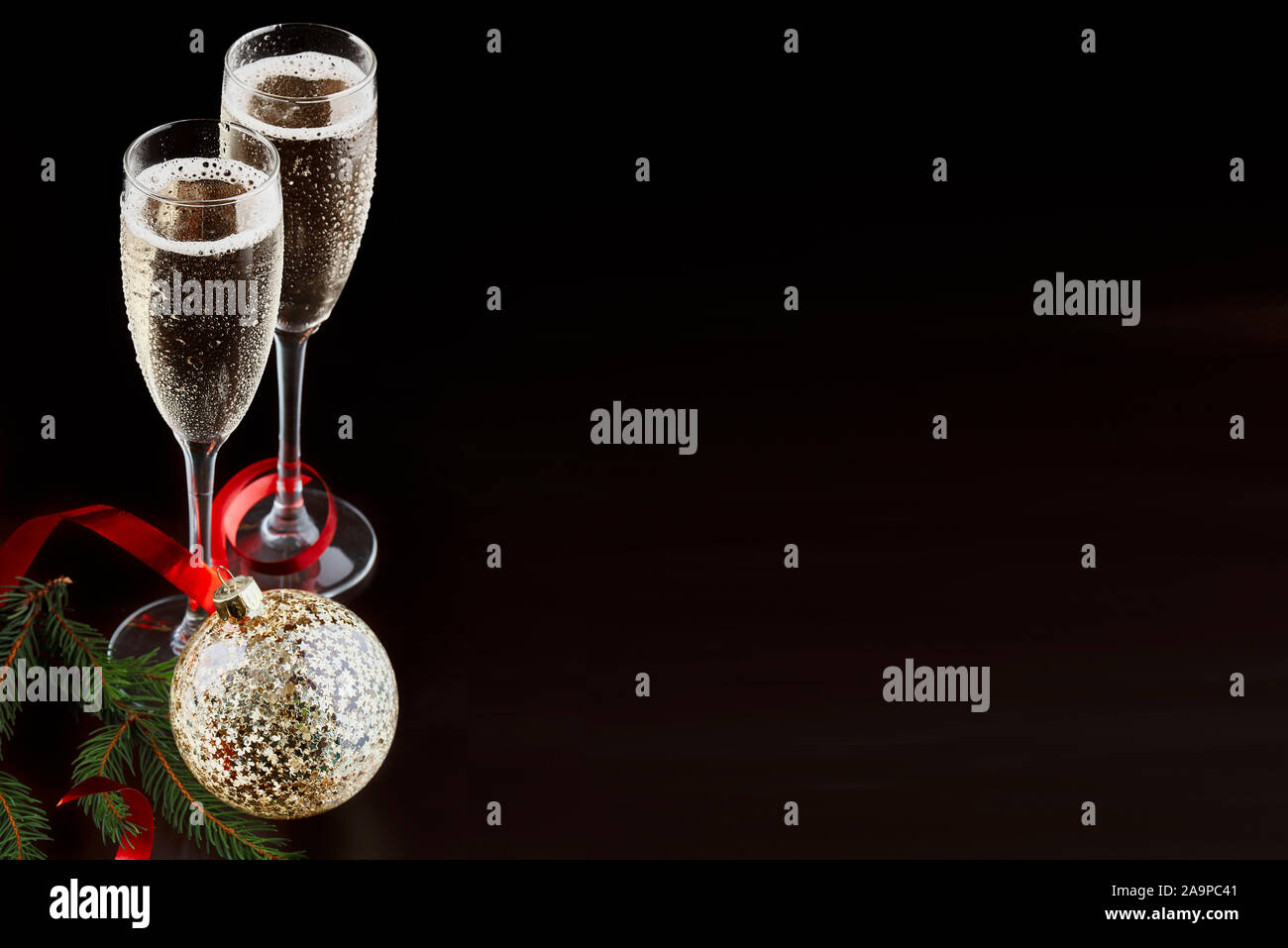 Natale e Capodanno celebrazione concetto: due bicchieri con bevanda frizzante e una bottiglia di champagne nel secchiello del ghiaccio con decorazioni di festa Foto Stock