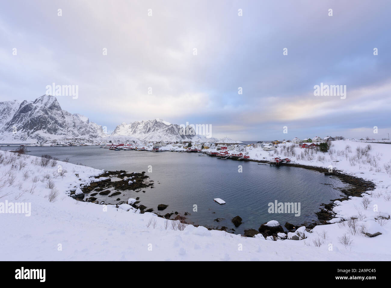 Bellissimo villaggio di Reine nelle Isole Lofoten in Norvegia. Coperta di neve paesaggio invernale al tramonto. Straordinaria attrazione turistica in circolo polare. Panora Foto Stock