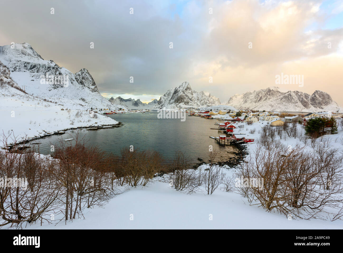 Bellissimo villaggio di Reine nelle Isole Lofoten in Norvegia. Coperta di neve paesaggio invernale al tramonto. Straordinaria attrazione turistica in circolo polare. Panora Foto Stock