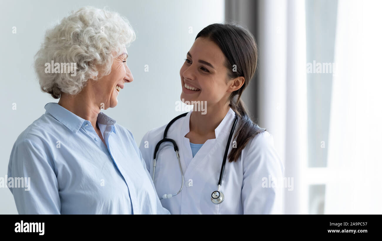 Sorridente femmina giovane infermiere assistere felice nonna contribuendo alla riabilitazione Foto Stock