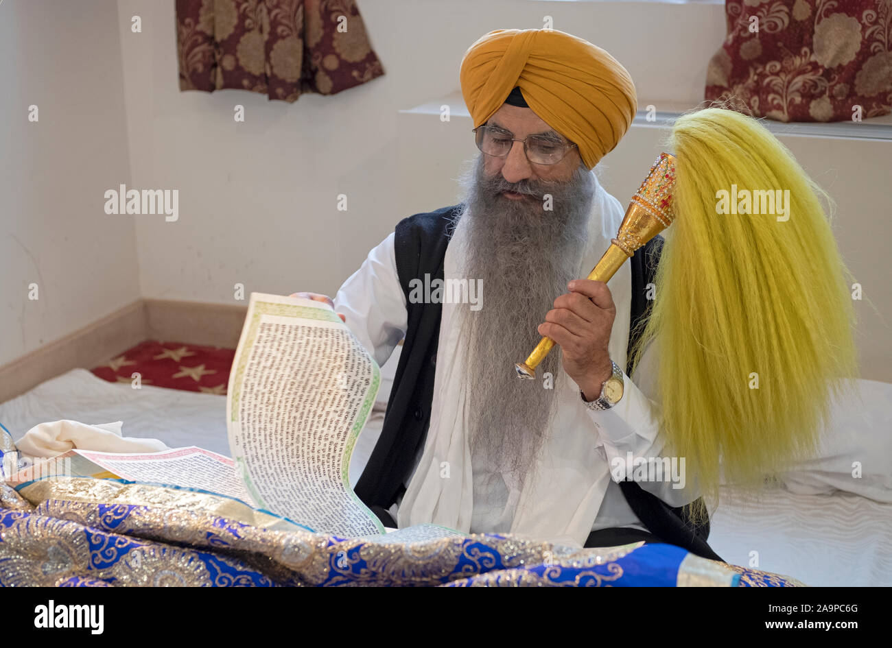 Un sacerdote Sikh in un turban legge dal Guru Granth Sahib libro sacro a un tempio in Richmond Hill, Queens, a New York City. Foto Stock