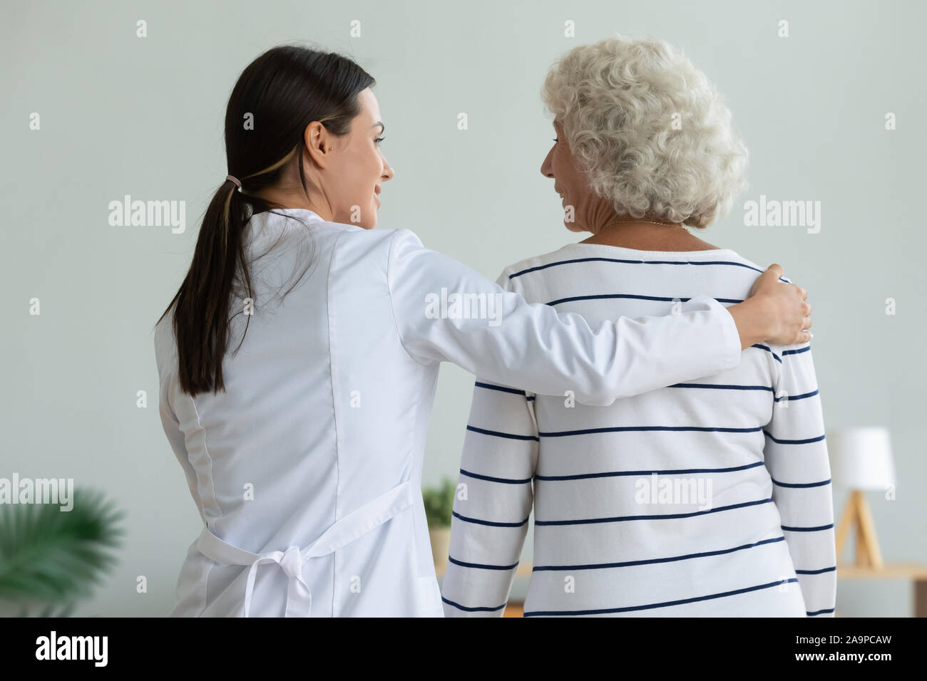 Femmina giovane fisioterapista aiutare feriti vecchia nonna a piedi del paziente, fisioterapia Foto Stock