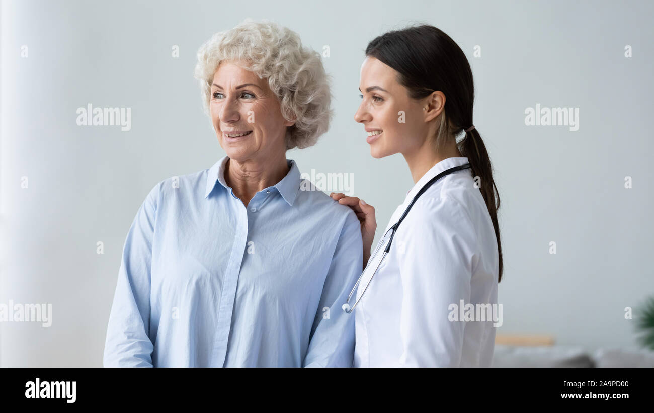 Felice vecchia nonna e la giovane donna caregiver infermiere guardando lontano Foto Stock
