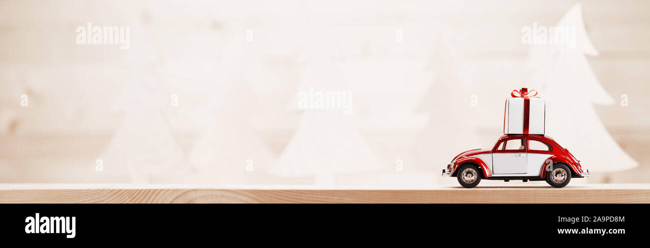 Rosso auto giocattolo con un regalo di Natale sulla foresta di legno sfondo , copia spazio per il testo Foto Stock
