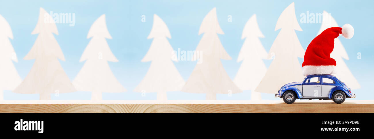 Blu auto giocattolo con il Natale di Santa Claus hat sulla foresta di legno sfondo , copia spazio per il testo Foto Stock