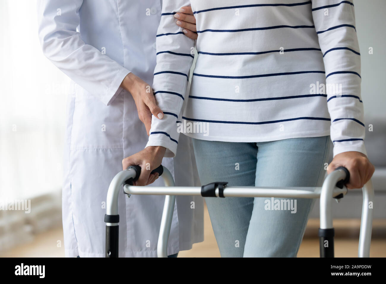 Infermiera femminile aiutando vecchia nonna paziente utilizzando il telaio a piedi, primo piano Foto Stock
