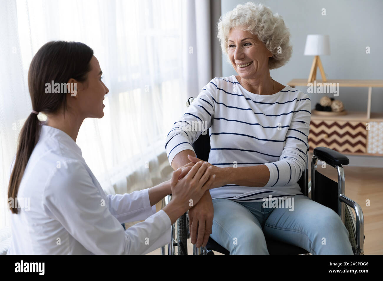 Caring femmina supporto infermiere anziano disabili donna paziente su sedia a rotelle Foto Stock