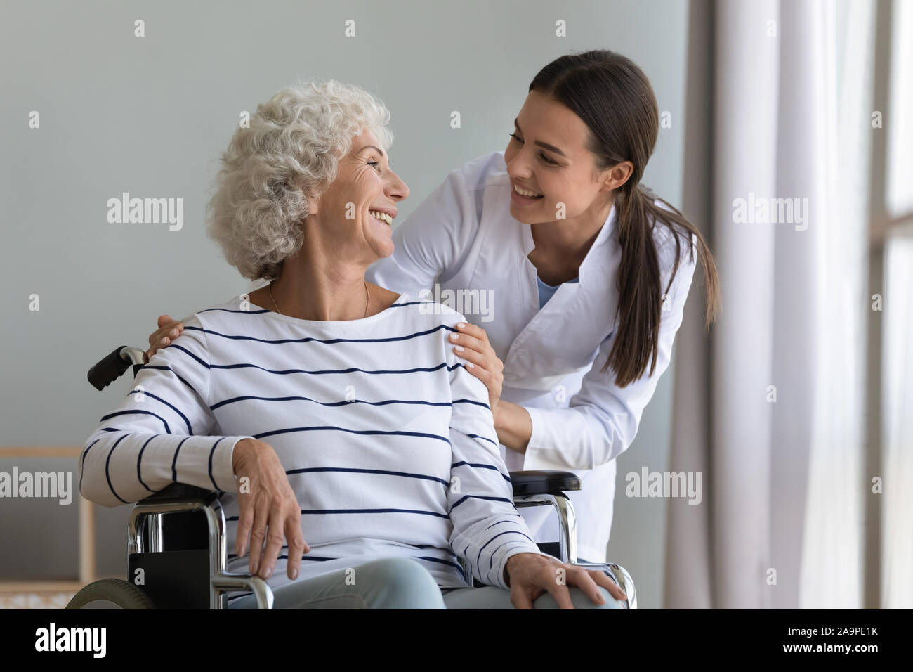 Felice giovane donna caregiver infermiere aiutare senior nonna sulla sedia a rotelle Foto Stock