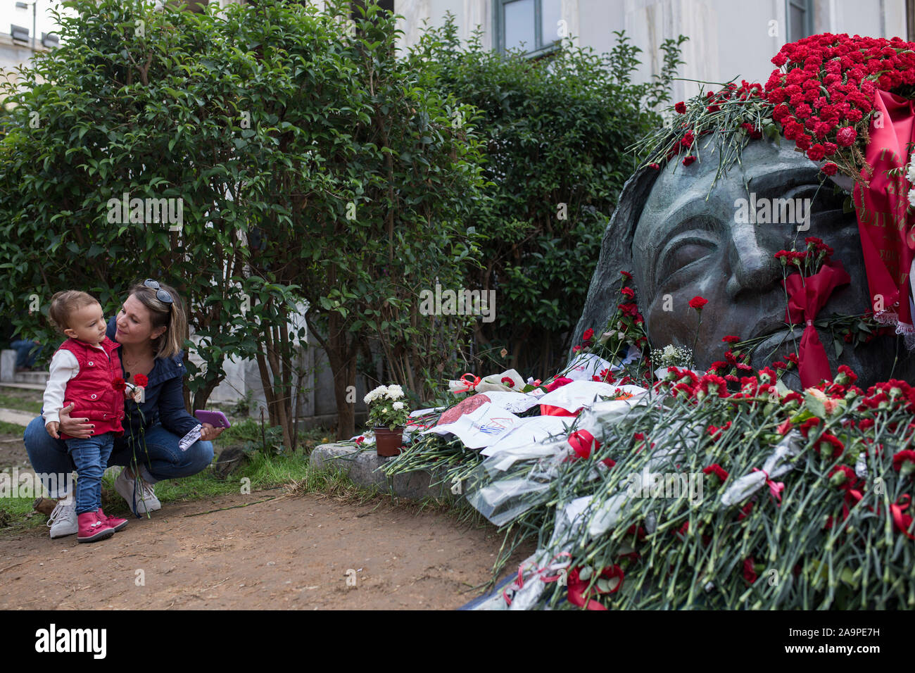 Atene, Grecia. 17 Nov, 2019. Una donna con un bambino stabilisce una Red Carnation presso il memoriale per le vittime della rivolta degli studenti su il quarantaseiesimo anniversario della sanguinosa repressione della rivolta studentesca contro la dittatura militare in Grecia. Il 17 novembre 1973, dimostranti, tra cui molti studenti, ha avuto per le strade. Credit: Socrates Baltagiannis/dpa/Alamy Live News Foto Stock