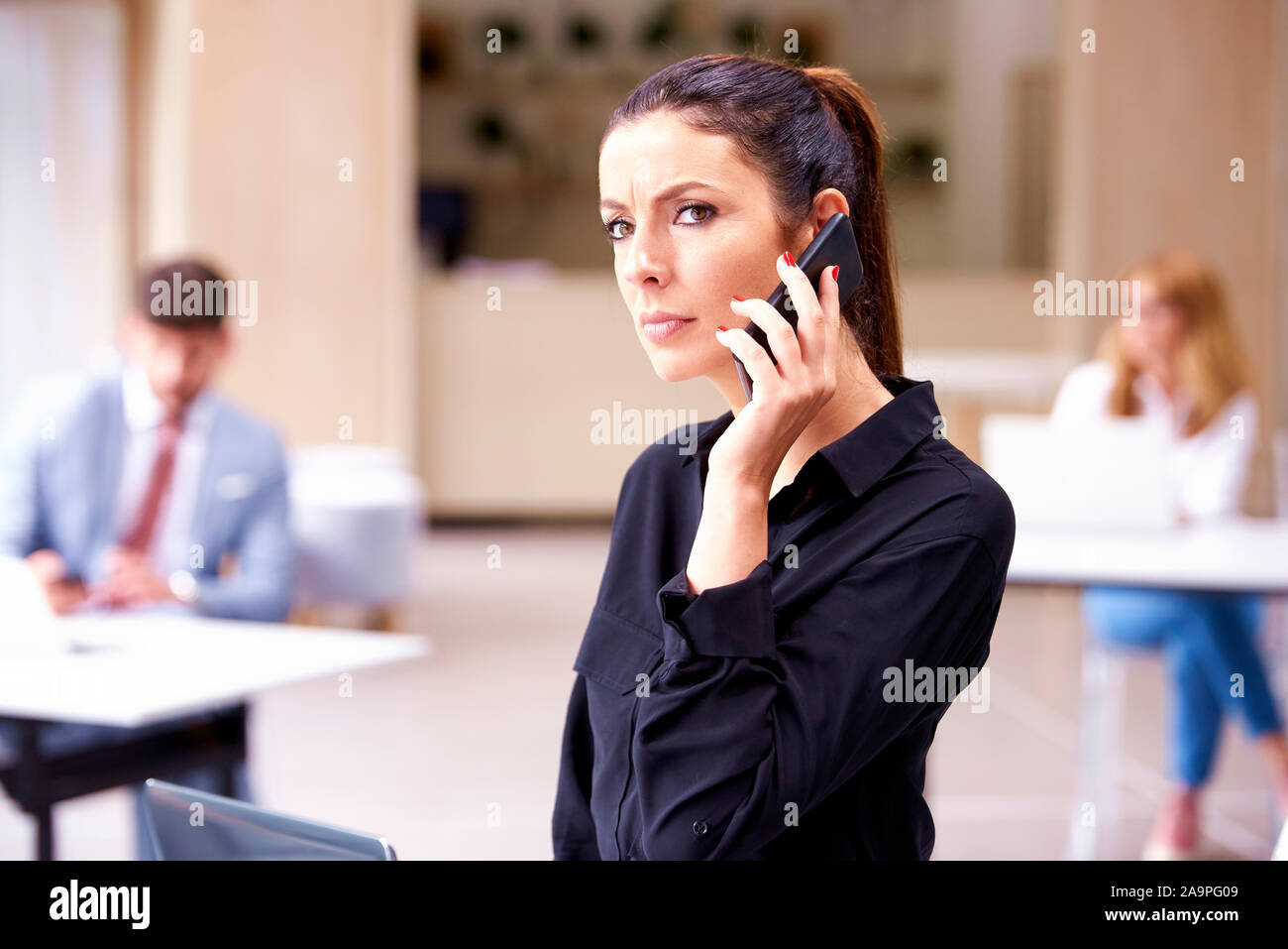 Colpo di grave di fronte imprenditrice avente un business chiamata mentre in piedi in ufficio. Foto Stock