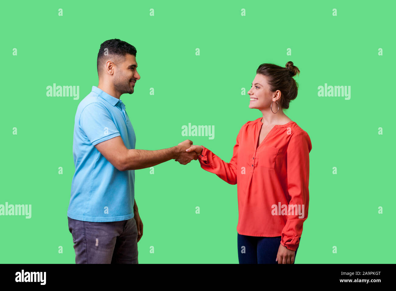 Ritratto di positiva gentile uomo e donna in abbigliamento casual in piedi, sorridente ad ogni altro e stringono le mani, giovane Primo incontro o un conoscente. è Foto Stock