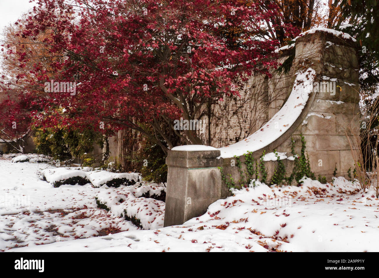 Il vecchio muro di pietra in un giardino coperto di neve Foto Stock