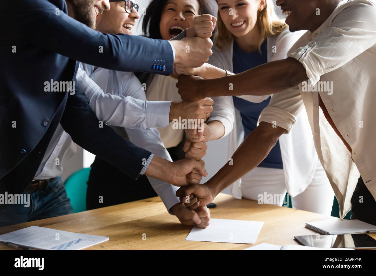 Overjoyed giovani vecchi razza mista di squadra rendendo piramide dei pugni. Foto Stock