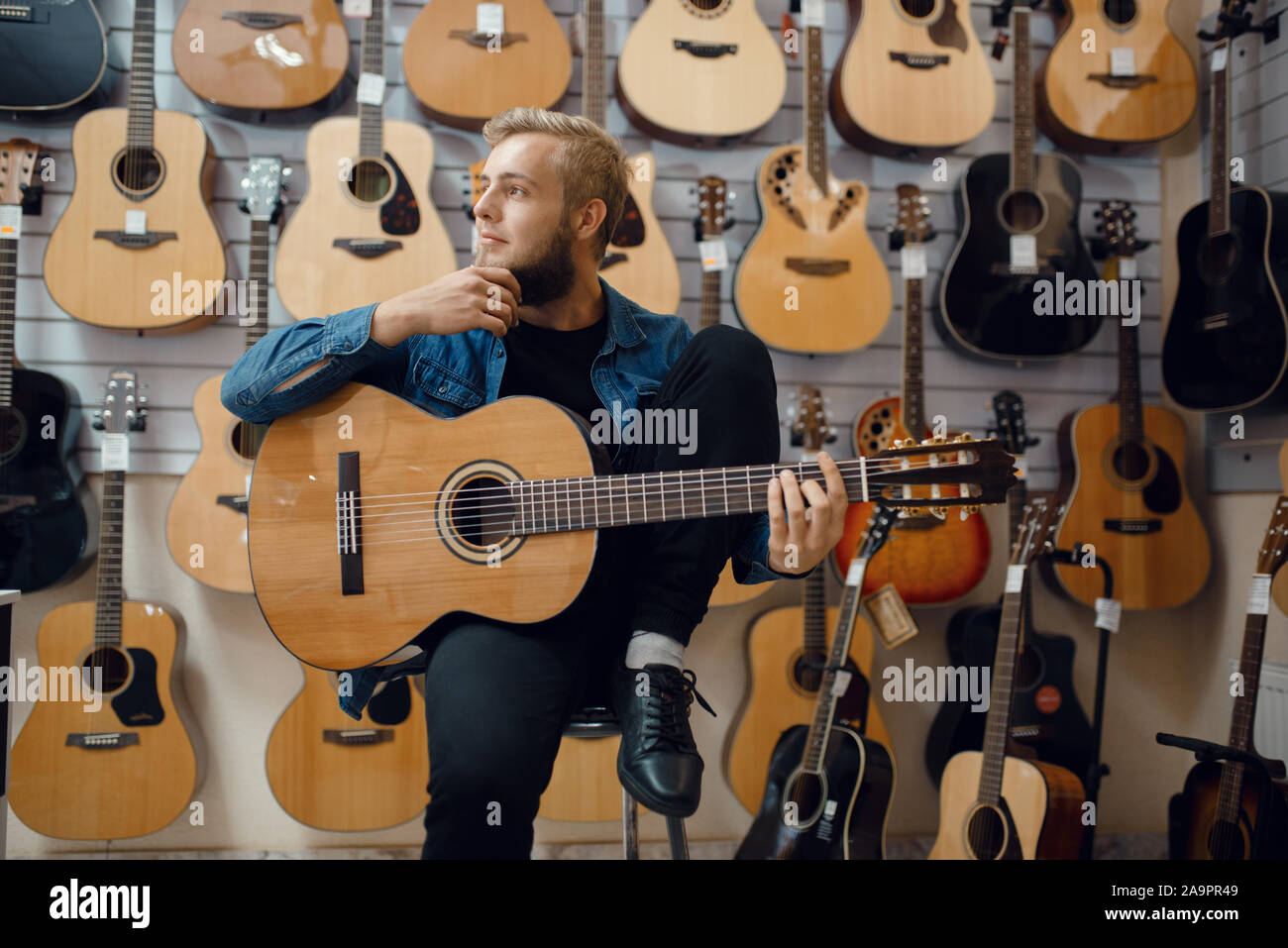 Giovane uomo gioca sulla chitarra acustica in music store Foto Stock