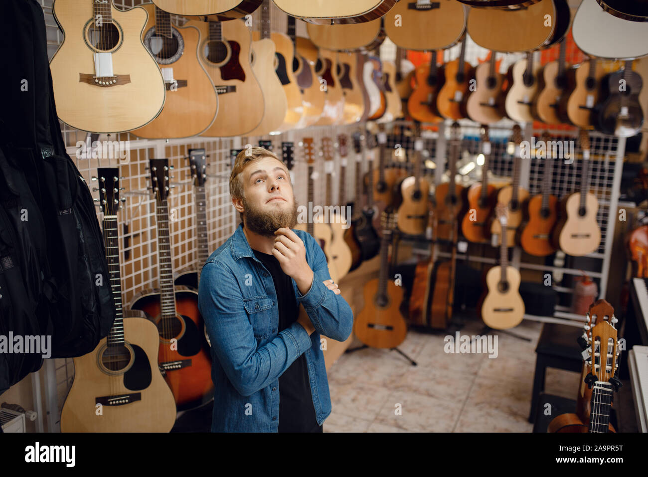 Giovane ragazzo scegliendo la chitarra acustica in music store Foto Stock