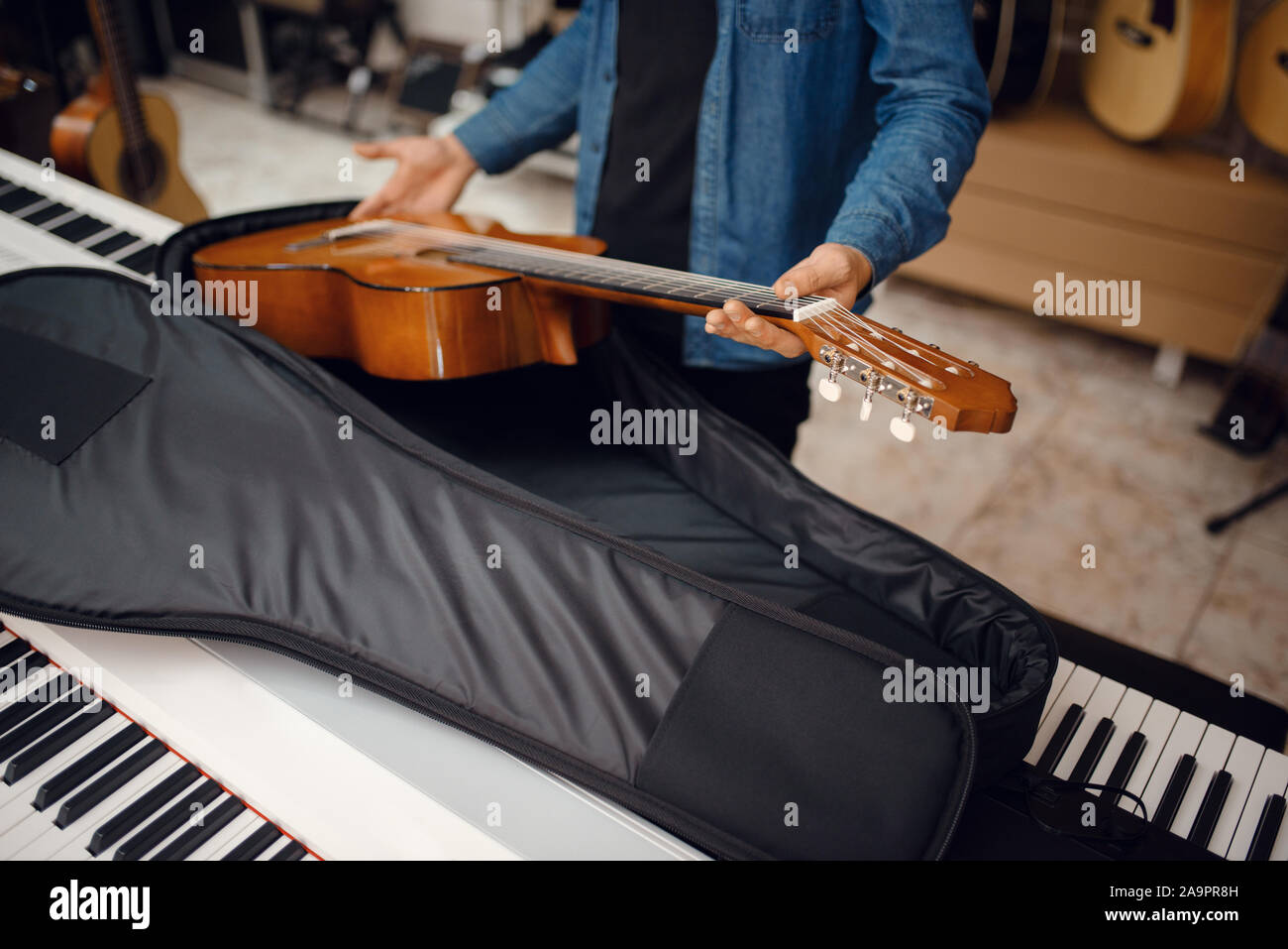 Il chitarrista mette la chitarra nel caso, music store Foto Stock