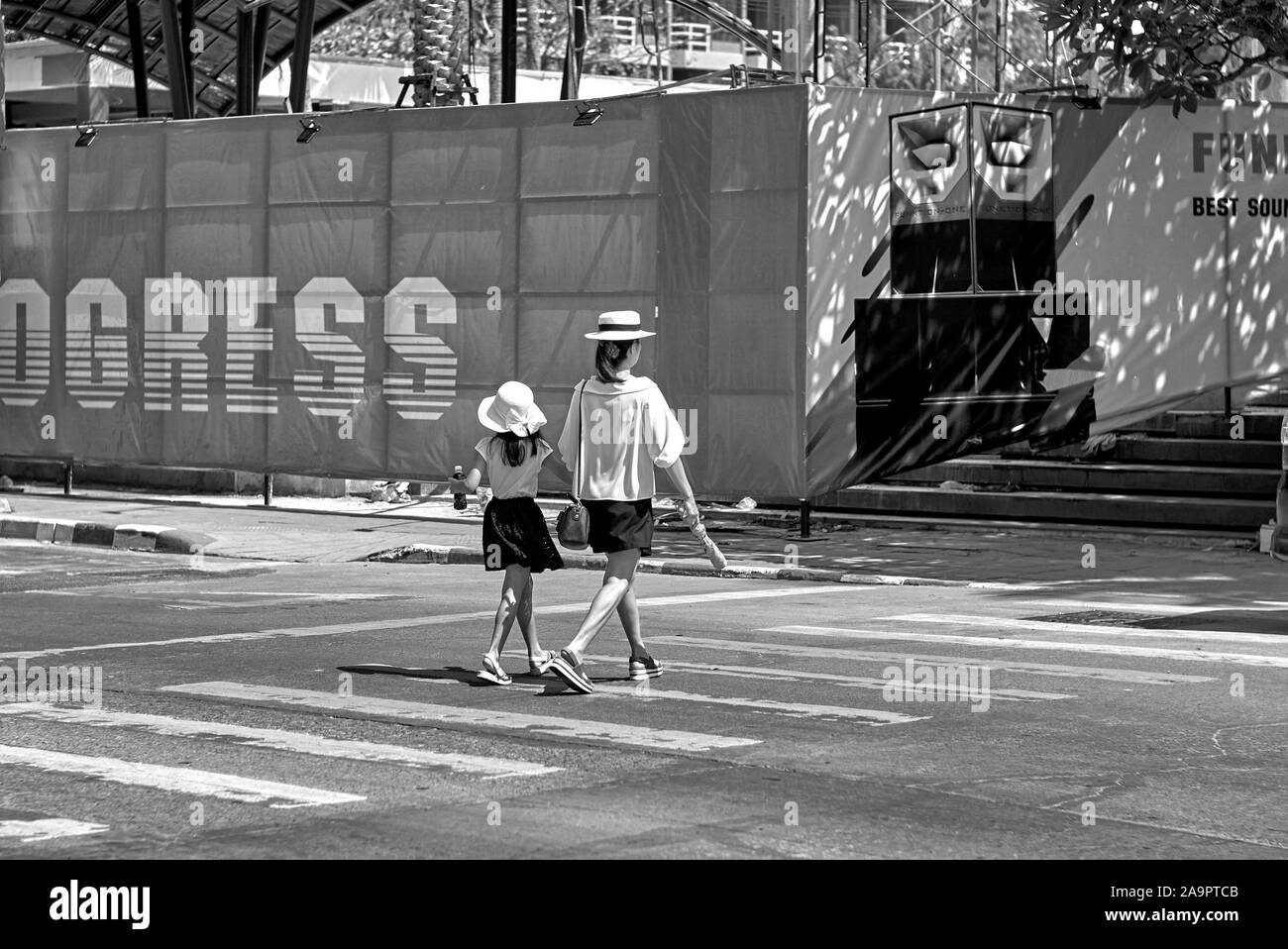 Madre e bambino che camminano attraverso la strada ad un incrocio zebra, tenendo le mani e tenendo al passo. Come la madre come la figlia Foto Stock