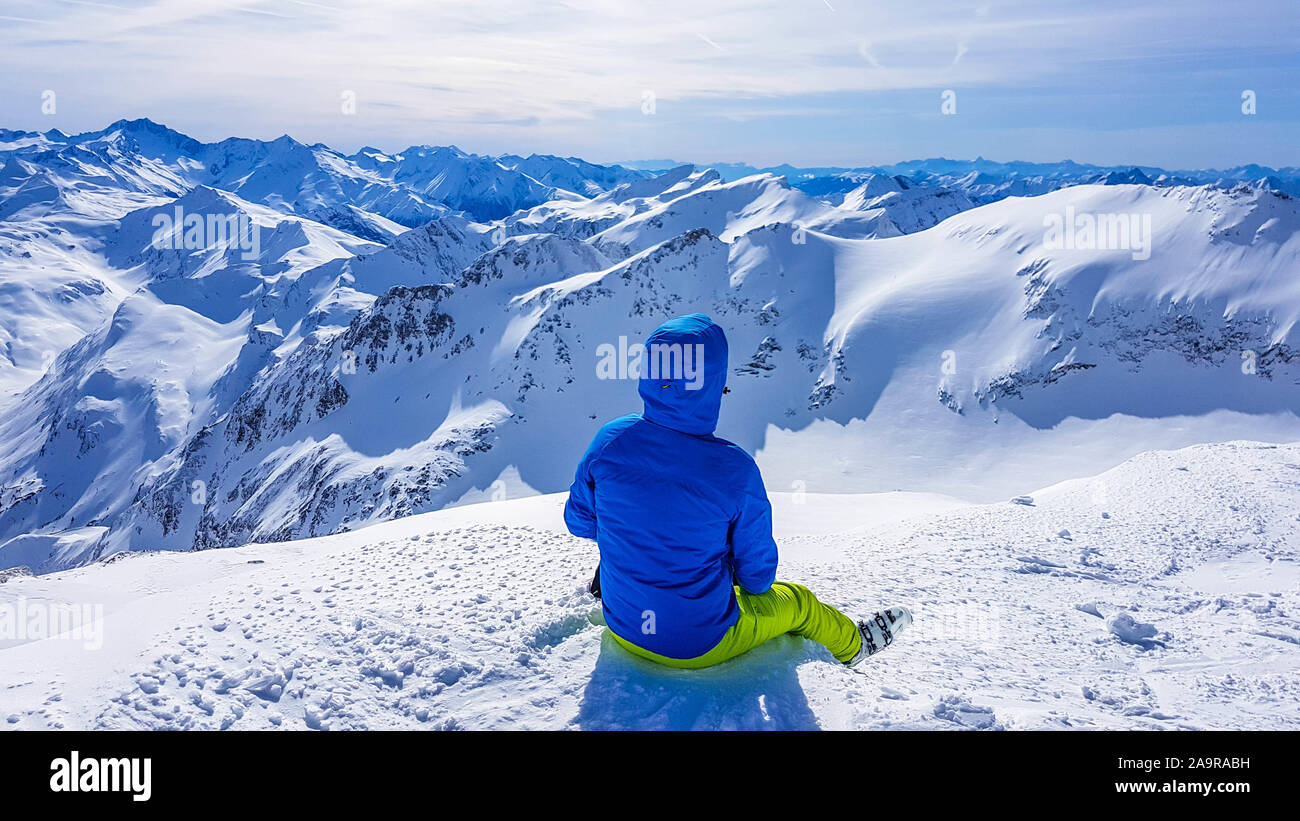 Sci giovane uomo seduto sulla neve in Mölltaler Gletscher, Austria, godendo della vista. Un sacco di neve in montagna. Interminabile catena delle Alpi. L'inverno ha vinto Foto Stock