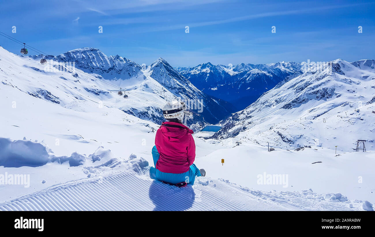 Snowboard ragazza seduta sulla neve in Mölltaler Gletscher, Austria, godendo della vista. Un sacco di neve in montagna. Interminabile catena delle Alpi. Inverno wo Foto Stock