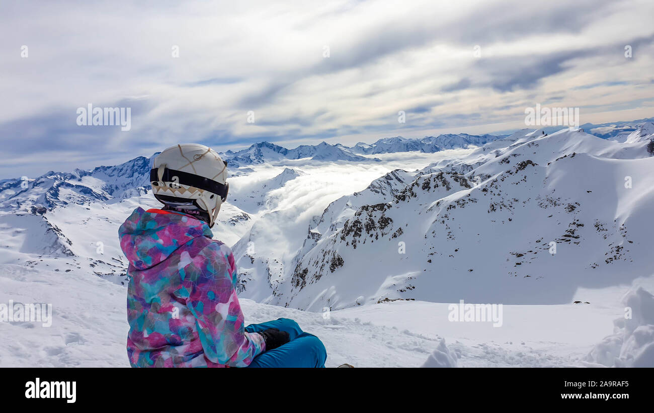 Snowboard ragazza seduta sulla neve in Mölltaler Gletscher, Austria, godendo della vista. Un sacco di neve in montagna. Interminabile catena delle Alpi. Inverno wo Foto Stock