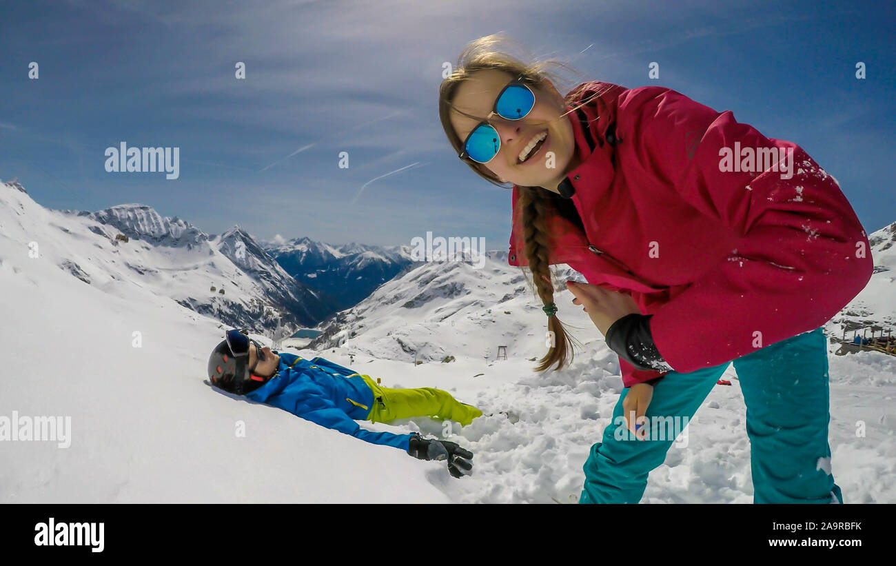 Un paio di sci outfits giocando nella polvere di neve. Il ragazzo è disteso sulla neve e una ragazza sorride alla telecamera. Trascorrere del tempo insieme. Infinite Foto Stock