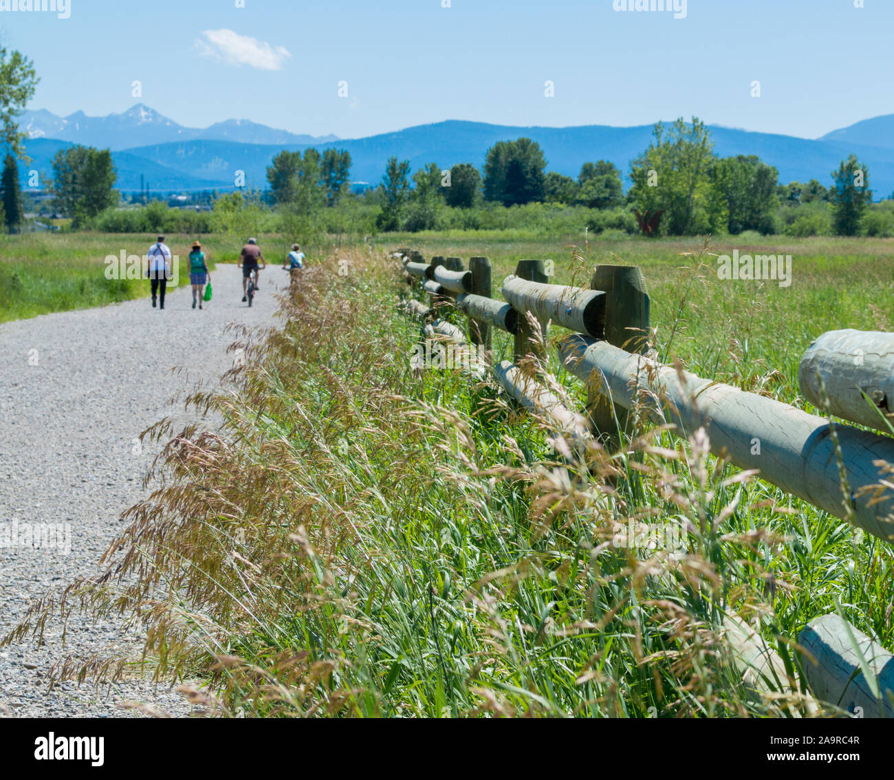4 gli escursionisti e i ciclisti che viaggiano lungo un outdoor sentiero di ghiaia a Bozeman, Montana con il maestoso Bridger montagne in distanza Foto Stock