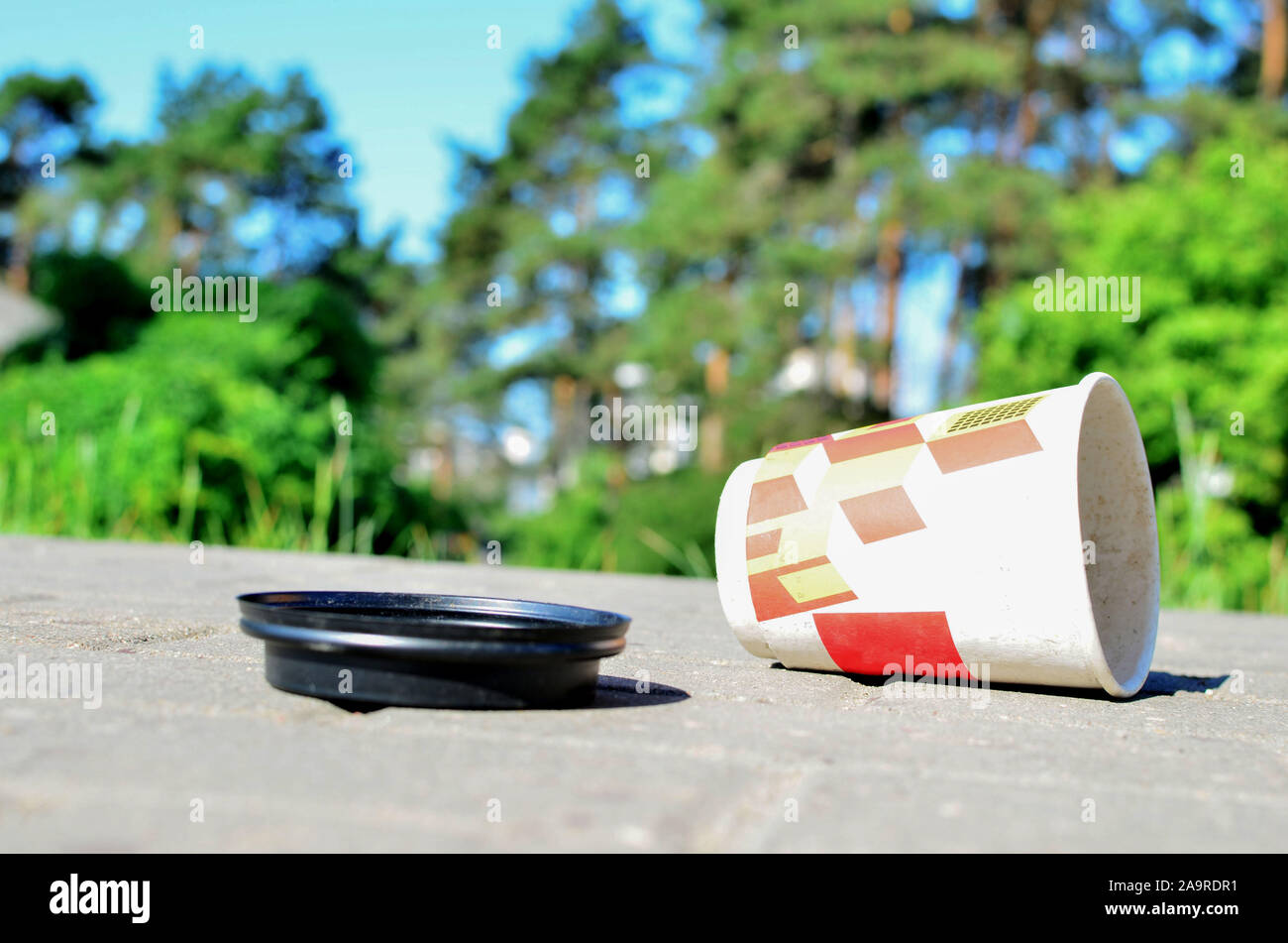 Scartato tazza da caffè in sulla terra. Le persone a sinistra dietro il cestino. Il concetto di inquinamento della natura e dell'ambiente, sfondo, tessitura Foto Stock