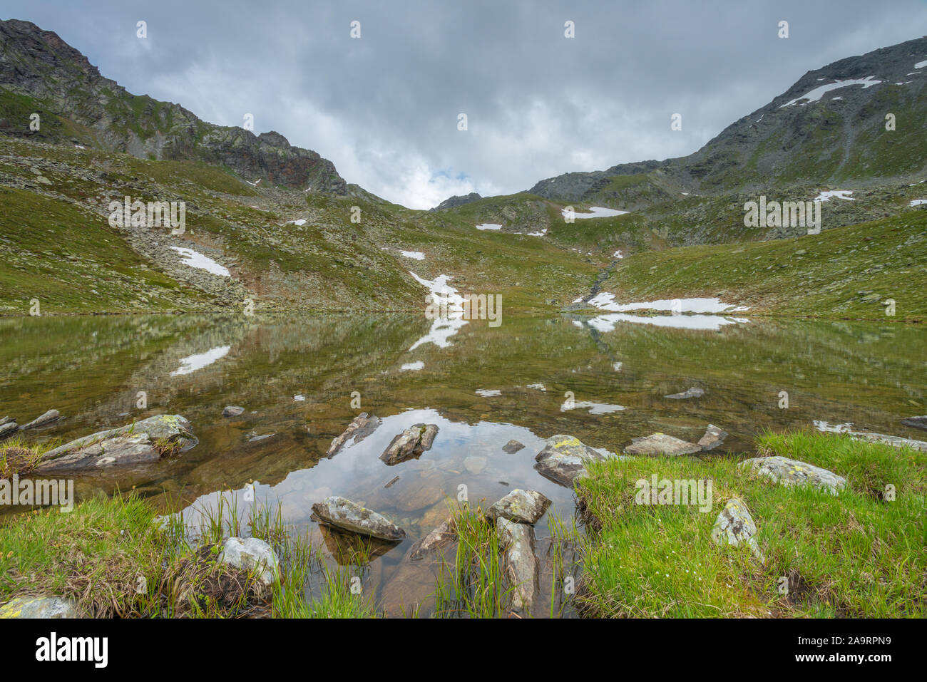 Kofler Vedi, Kofler lago delle Alpi italiane, piccolo lago smeraldo con fondo roccioso e scuro delle montagne che lo circondano. Lago erbosa banche. Foto Stock