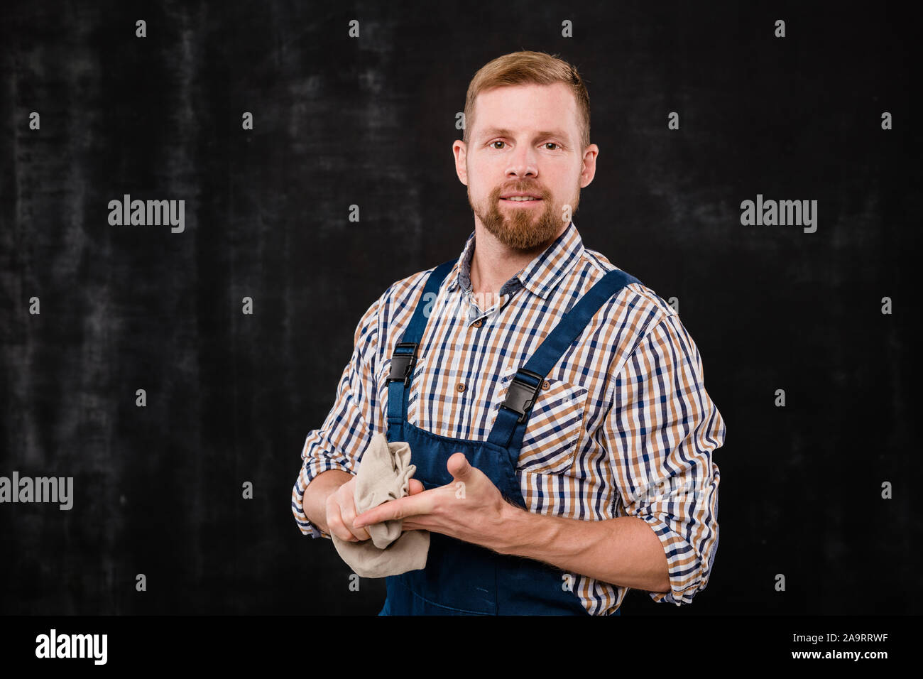 Giovani barbuto meccanico o un tecnico specializzato in abbigliamento da lavoro lavarsi le mani dopo il lavoro Foto Stock