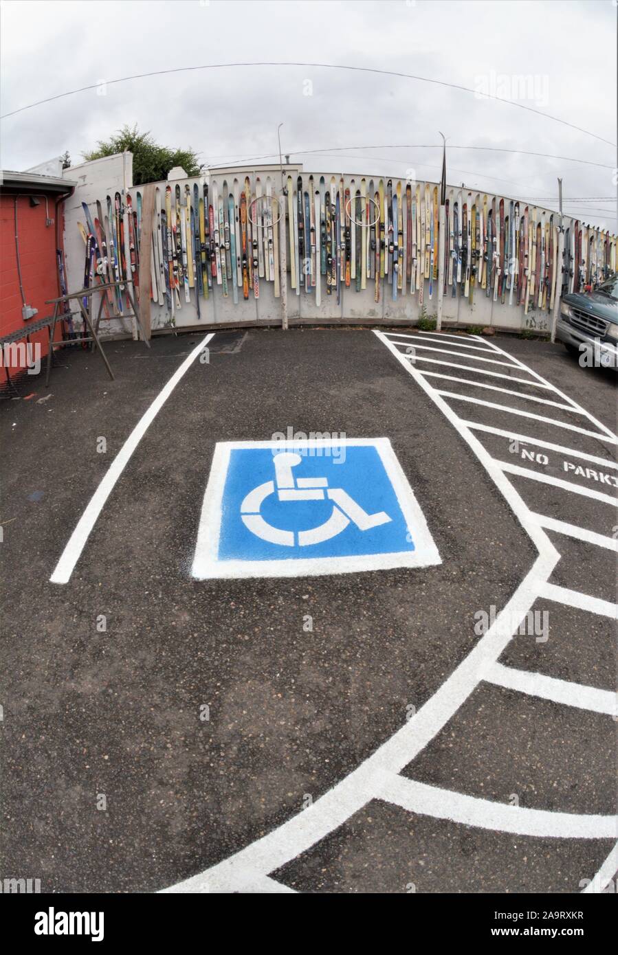 Gli sci sono usati per coprire la recinzione nel parcheggio come oggetti d'arte dietro un parcheggio per disabili in Bend Oregon USA Foto Stock