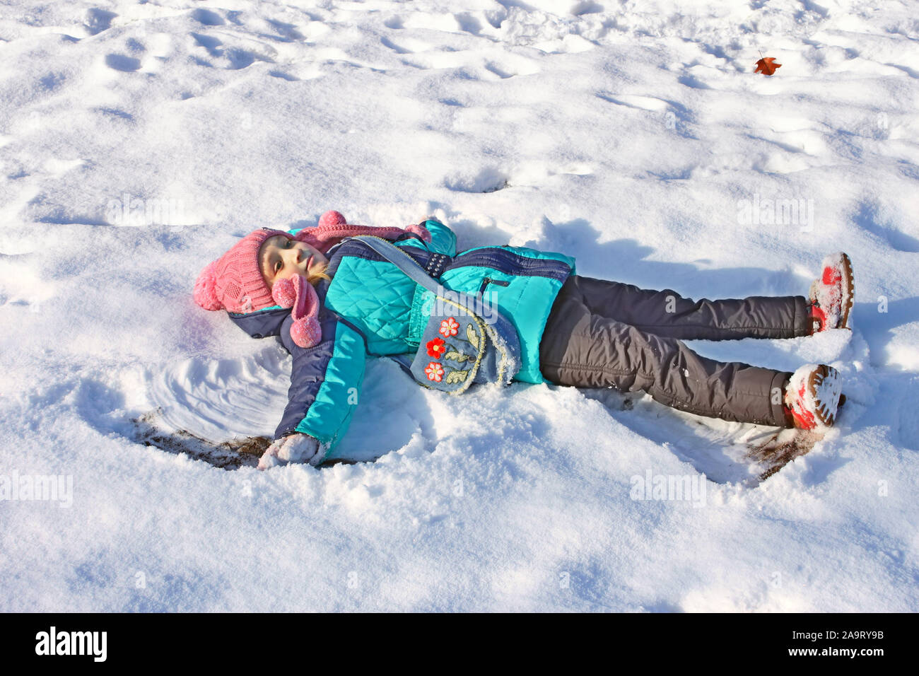 Bellissima bambina sul retro giacente in una neve poco profonda in un soleggiato inverno meteo Foto Stock