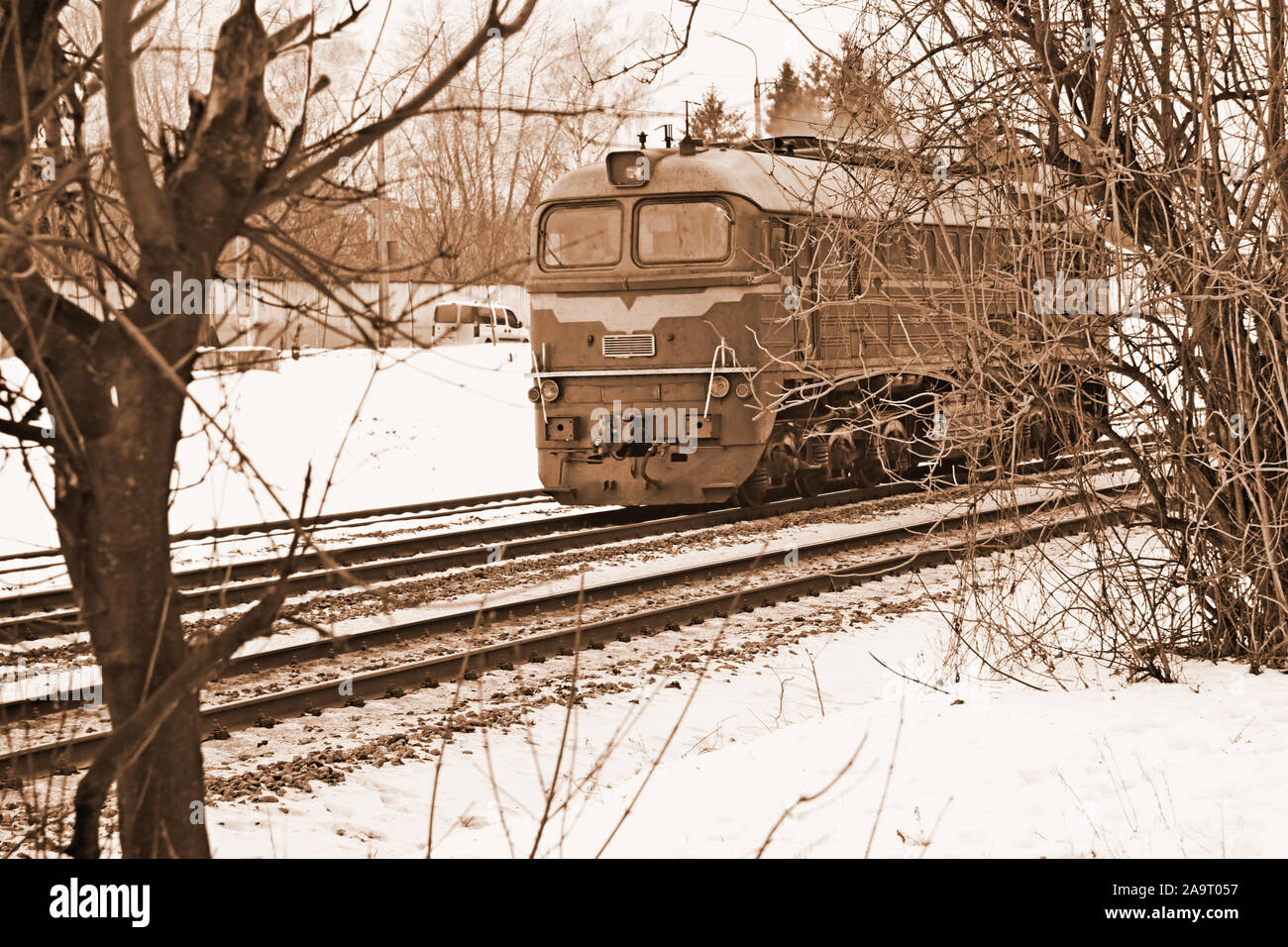 Unica locomotiva diesel si muove attraverso i binari ferroviari in inverno, seppia Foto Stock