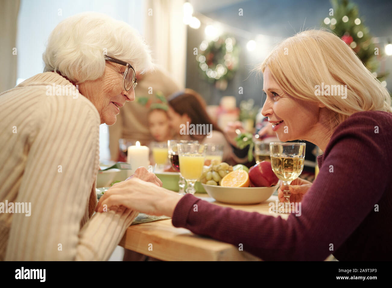 Donna Senior in occhiali e sua figlia bionda in chat da servita tabella Foto Stock