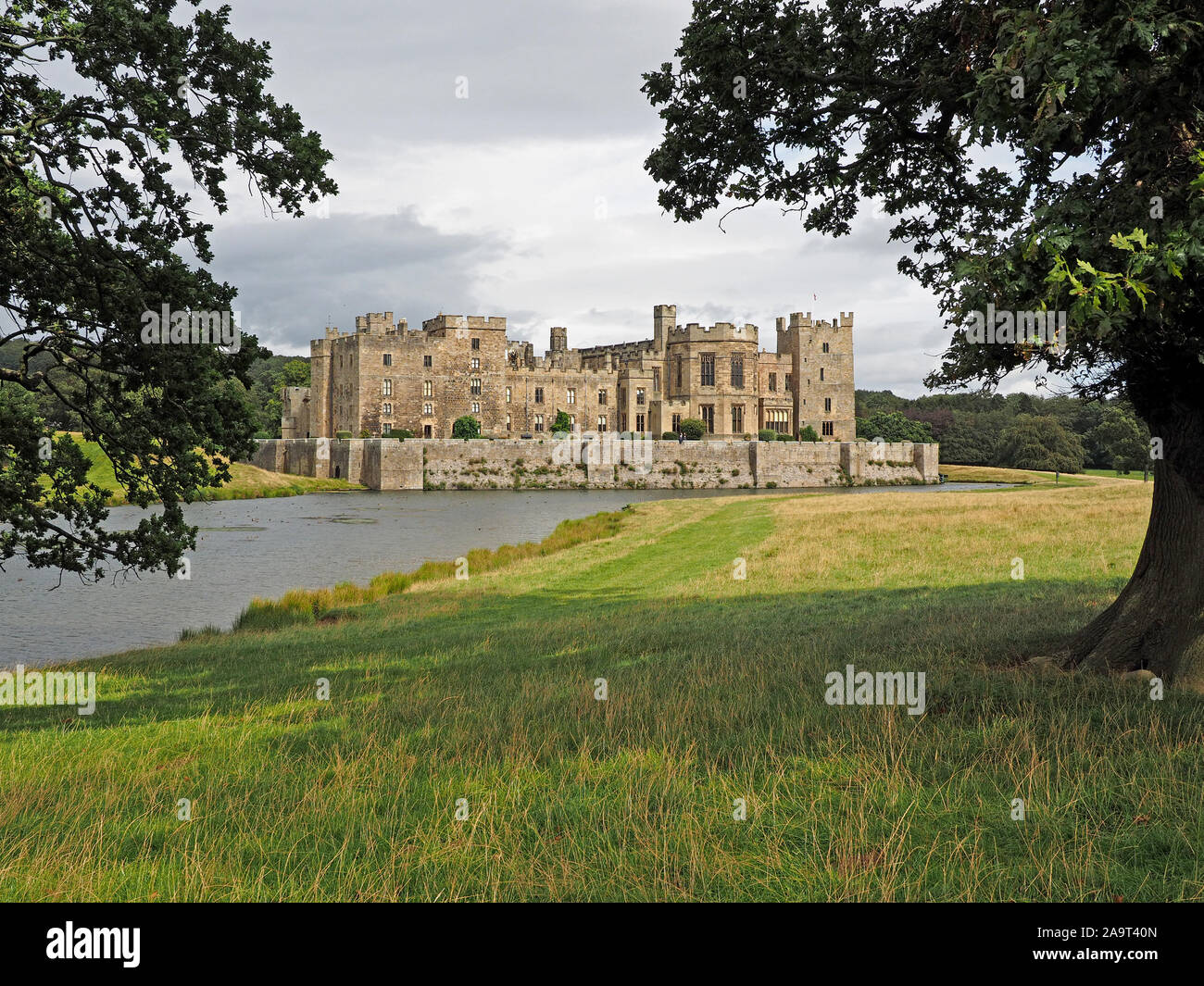 Vista del paesaggio del XIV secolo Raby Castle attraverso il lago in ampi terreni nella Contea di Durham, England, Regno Unito Foto Stock