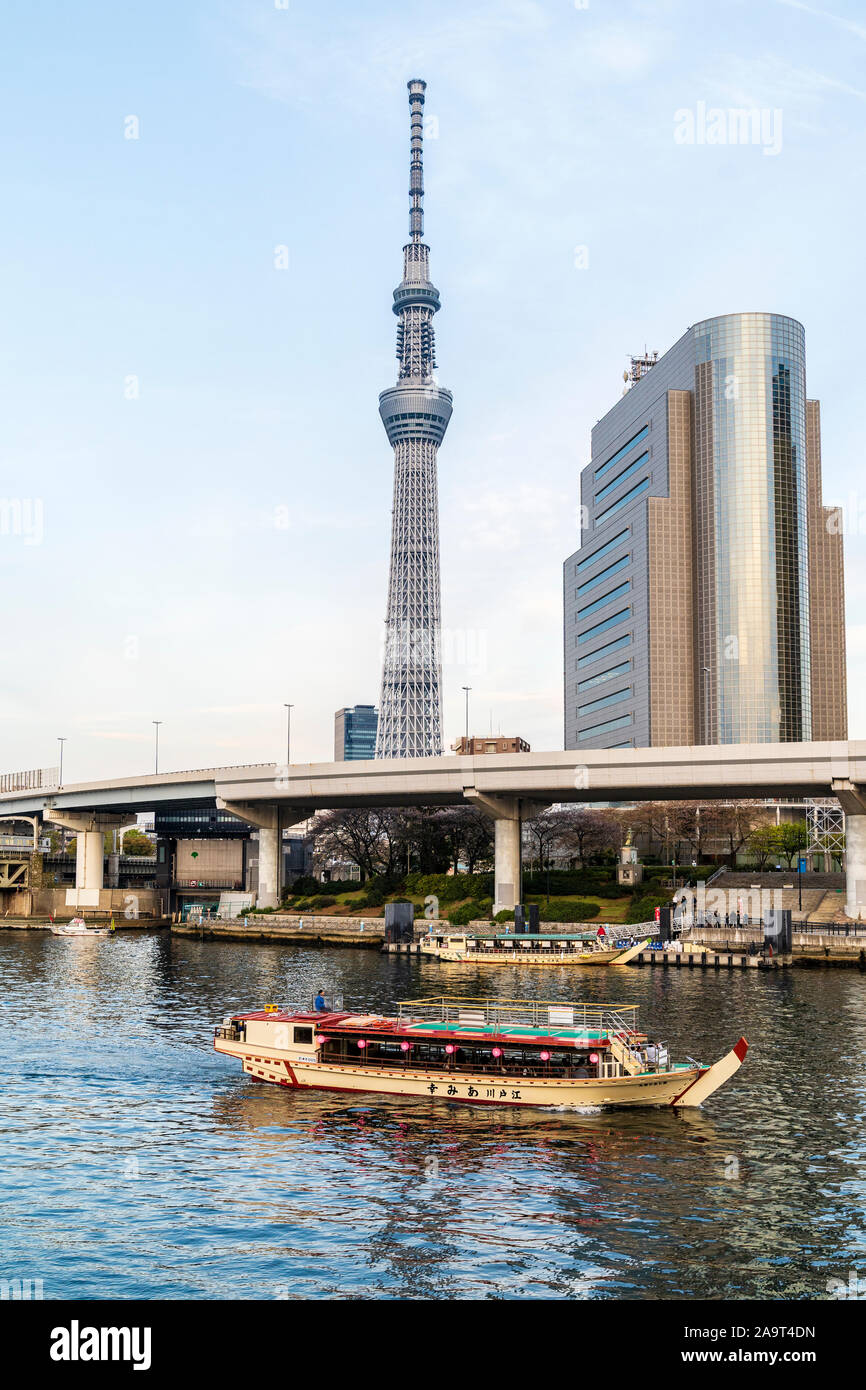 Tokyo Skytree e Sumida Ward ufficio edificio visto dal Tempio di Asakusa. Primo piano, Sumida River con una crociera sul fiume imbarcazione attraccata a tubo piccolo. Ora d'oro Foto Stock