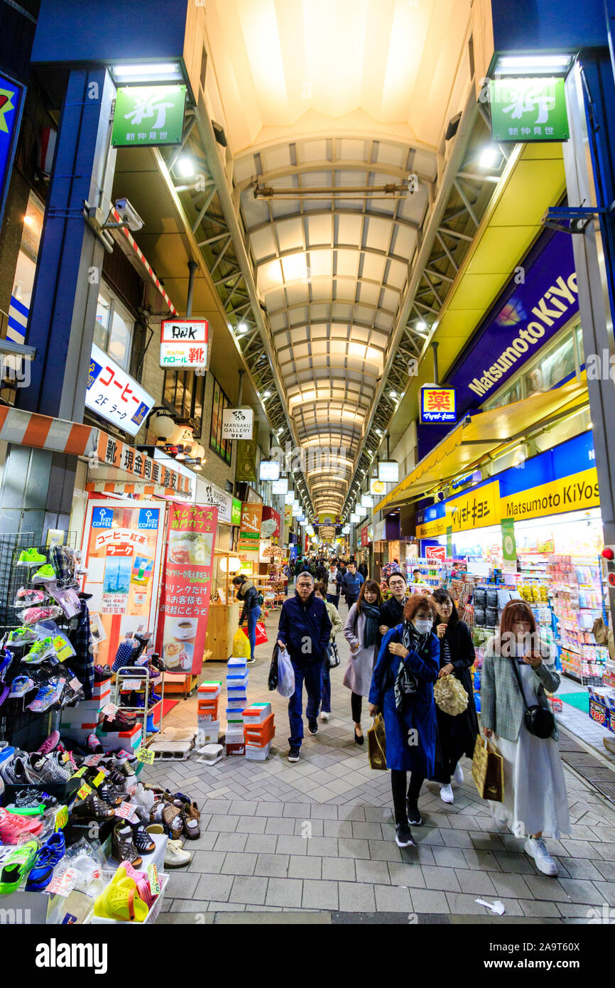 Tokyo, Asakusa. Oggetto shopping arcade off Nakamise Dori, street al Tempio di Asakusa. Vista lungo interno con gli acquirenti a piedi verso il visualizzatore. Notte. Foto Stock