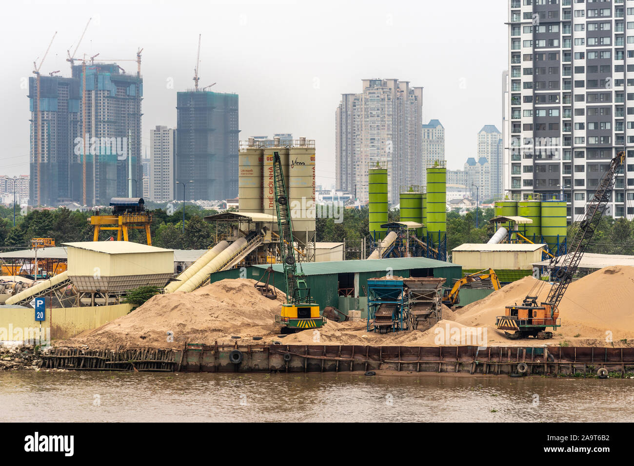 Ho Chi Minh City Vietnam - Marzo 12, 2019: canzone Sai Gon river. Primo piano di silos, gru e cumuli di sabbia sulla spiaggia a base di continuo in cui il cemento è m Foto Stock