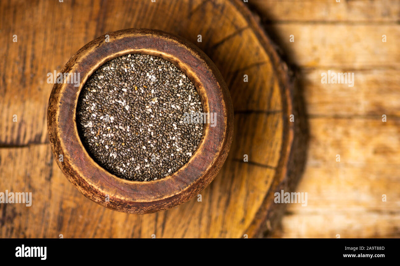 Chia semi in una ciotola su uno sfondo di legno vista superiore Foto Stock