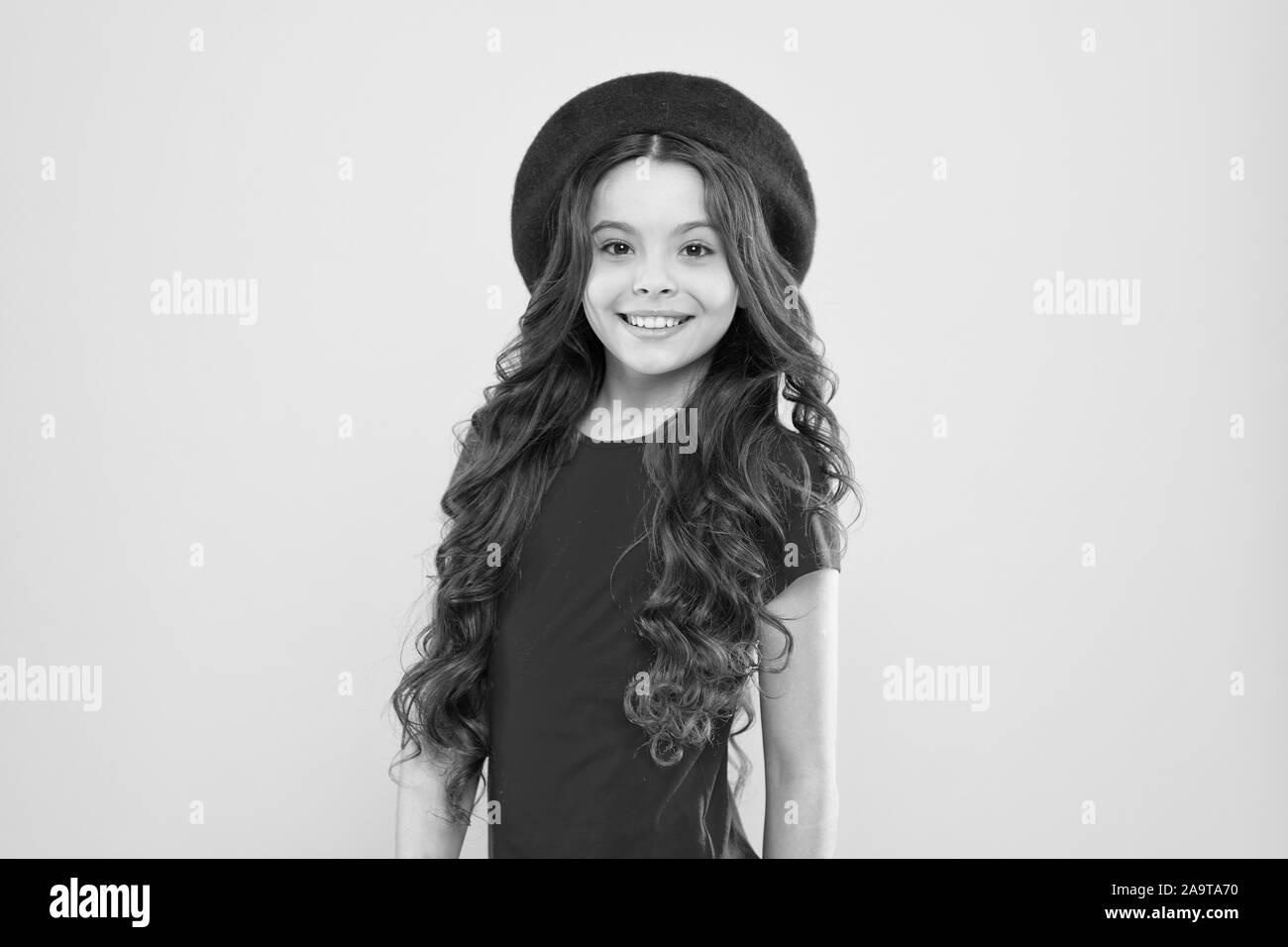 Bambino parigino su sfondo giallo. bambina in stile francese hat. infanzia. parrucchiere. estate moda e bellezza. Felice ragazza con lunghi capelli ricci in beret. ragazza parigina fa un figurone. Foto Stock