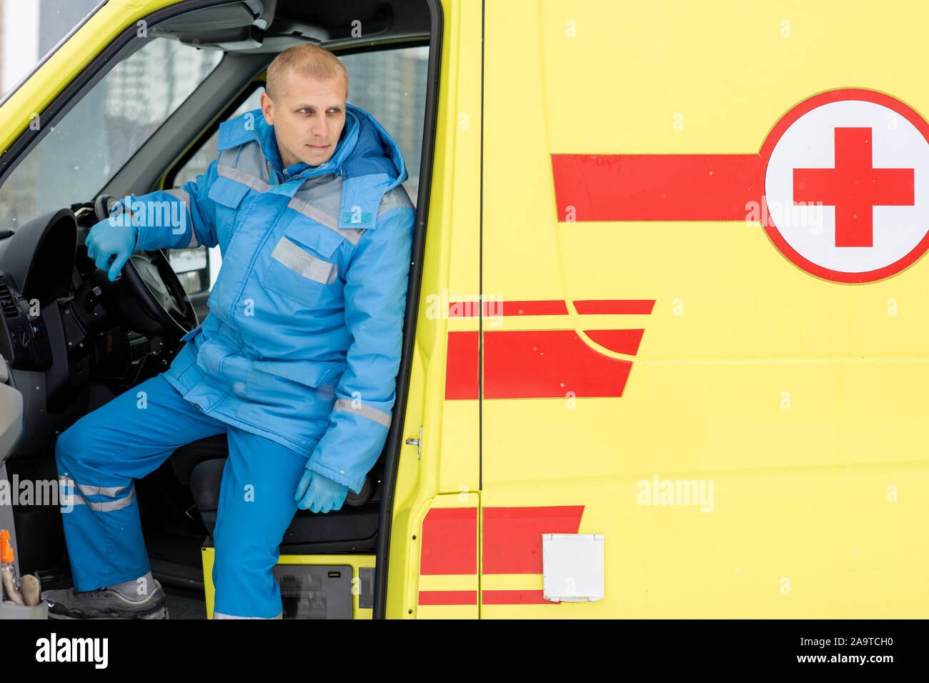 Autista di ambulanza seduta da sterzare durante l'attesa per i paramedici torna indietro Foto Stock