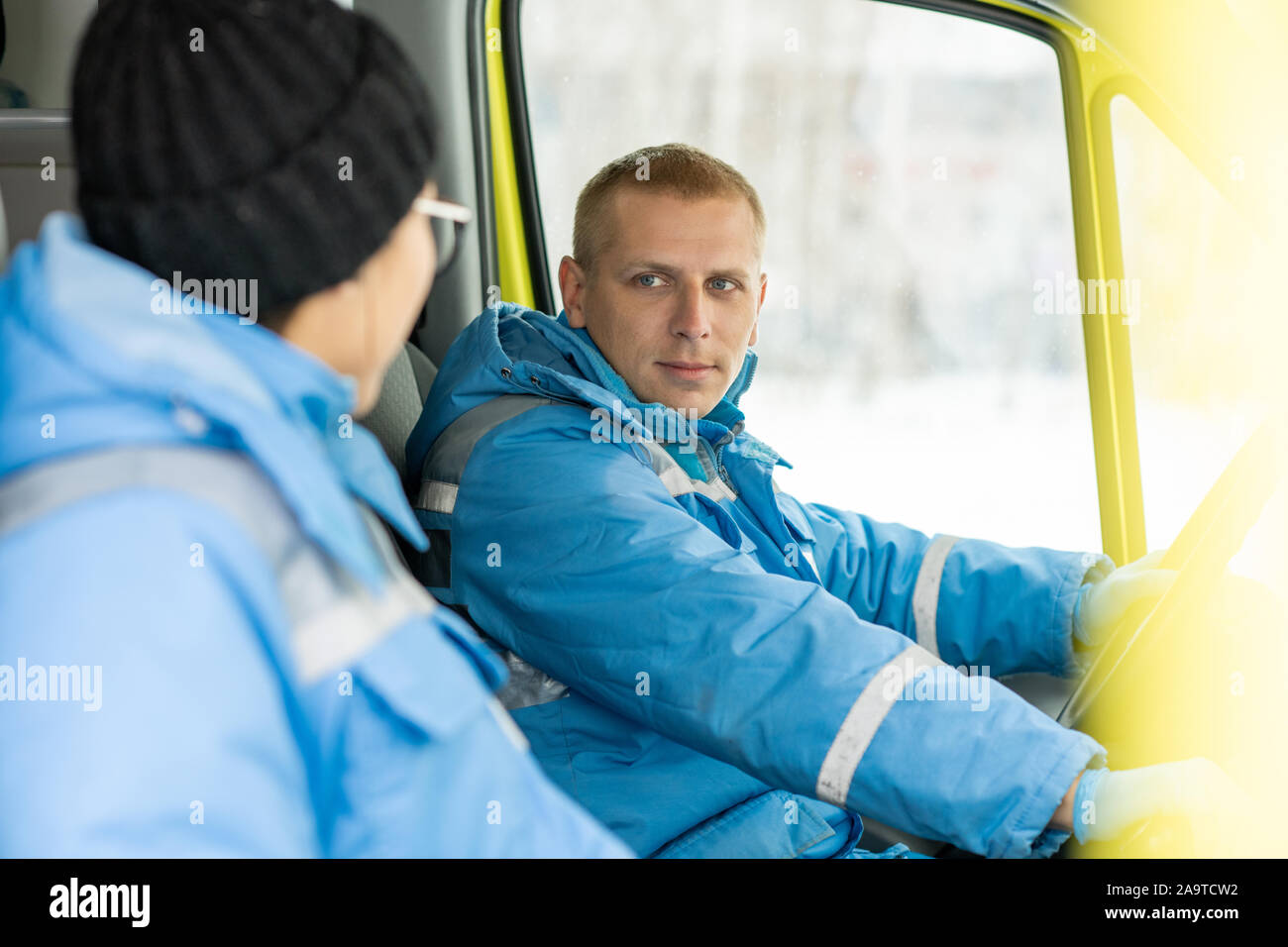 Il giovane driver di ambulanza parlando a femmina paramedico e sterzo Foto Stock